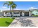Charming single-story home with a well-manicured lawn, paver driveway, and beautiful landscaping at 241 176Th Terrace E Dr, Redington Shores, FL 33708