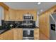 Well-lit kitchen features stone countertops, stainless steel appliances, and wood cabinets at 241 176Th Terrace E Dr, Redington Shores, FL 33708