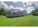 Expansive backyard featuring a screened-in pool enclosure and lush green lawn at 27528 Water Ash Dr, Wesley Chapel, FL 33544