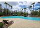 Stunning community pool with lounge chairs and palm trees under a partly cloudy sky at 27528 Water Ash Dr, Wesley Chapel, FL 33544
