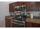 Close-up of a stove with stainless steel oven, microwave and dark brown cabinets at 27528 Water Ash Dr, Wesley Chapel, FL 33544