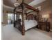This is a lovely main bedroom featuring a four-poster bed, neutral color palette, and access to the lanai at 27528 Water Ash Dr, Wesley Chapel, FL 33544
