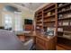 Cozy office space featuring custom built-in shelving, a large wooden desk and rolling chair at 27528 Water Ash Dr, Wesley Chapel, FL 33544