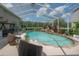 Screened pool with rock features and waterfall, landscaped garden, seating, and pond view for relaxation at 27528 Water Ash Dr, Wesley Chapel, FL 33544