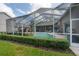 Inviting screened-in pool area with patio furniture, tropical plants and well-manicured hedges at 27528 Water Ash Dr, Wesley Chapel, FL 33544