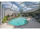 Sparkling pool with rock features inside screened enclosure, surrounded by lush landscaping and outdoor seating at 27528 Water Ash Dr, Wesley Chapel, FL 33544