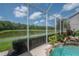 Backyard view from pool screen showing lush landscaping, backyard pond, and water feature at 27528 Water Ash Dr, Wesley Chapel, FL 33544