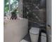 Commode with luxurious marble walls, sleek toilet, and floating counter with decorative accents at 27528 Water Ash Dr, Wesley Chapel, FL 33544