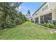 This backyard features a lawn, a screened lanai, and wooded surroundings, creating a serene outdoor space at 2844 Jacob Crossing Ln, Holiday, FL 34691