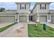 View of townhomes with light exteriors and single-car garages, accented with landscaping at 2844 Jacob Crossing Ln, Holiday, FL 34691