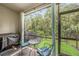 Relaxing screened patio with an outdoor table set, grill, and view of the green backyard at 2844 Jacob Crossing Ln, Holiday, FL 34691