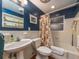 Bathroom featuring a pedestal sink, decorative mirror, and a bathtub with a patterned shower curtain at 308 Cedar Ln, Largo, FL 33770