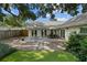 Back patio features a dining table, neutral pavers, pea gravel, a manicured lawn, and access to the home's interior at 3315 W Hawthorne Rd, Tampa, FL 33611