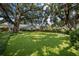 Expansive backyard featuring lush artificial turf and mature trees providing ample shade and a serene outdoor space at 3315 W Hawthorne Rd, Tampa, FL 33611