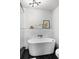 Bright bathroom featuring a white soaking tub, marble half-wall, glass shower, and modern light fixture at 3315 W Hawthorne Rd, Tampa, FL 33611