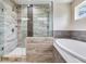 Bathroom featuring a glass shower with stone accents, a white soaking tub, tiled flooring, and a small window at 3503 W Price Ave, Tampa, FL 33611