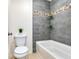 Bathroom with a modern bathtub, grey tile surround with decorative accent tile and glass shelves at 3503 W Price Ave, Tampa, FL 33611