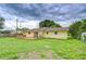 View of the back exterior of the yellow home showcasing a wooden deck and a well-maintained lawn at 40019 Pretty Redbird Rd, Zephyrhills, FL 33540