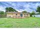 Back exterior view of yellow house featuring wooden deck, sliding door, and well maintained grass at 40019 Pretty Redbird Rd, Zephyrhills, FL 33540