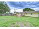 Backyard view of the yellow home featuring a wooden deck, sliding door, and healthy grass at 40019 Pretty Redbird Rd, Zephyrhills, FL 33540