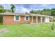 The red brick home features white trimmed windows with an expansive green front yard at 40019 Pretty Redbird Rd, Zephyrhills, FL 33540