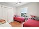 Cozy bedroom featuring wood floors, closet, window and two twin beds with red comforters and decorative pillows at 4926 Pennecott Way, Wesley Chapel, FL 33544