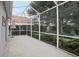 Enclosed patio featuring concrete floor, a screen enclosure, with landscaping and lush green ferns viewed beyond at 4926 Pennecott Way, Wesley Chapel, FL 33544