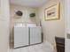 Functional laundry room featuring a washer, dryer, shelf, and stylish decor at 4953 Bacopa S Ln # 205, St Petersburg, FL 33715
