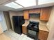 Galley kitchen featuring a black refrigerator and range, plus light countertops and wooden cabinetry at 5042 Terrace Village Ln, Tampa, FL 33617