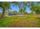 Serene backyard featuring a screened-in pool, fire pit, and mature trees at 538 Bamboo Ln, Clearwater, FL 33764