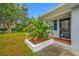 Close up view of the front door and beautifully landscaped flower bed with tropical plants at 538 Bamboo Ln, Clearwater, FL 33764