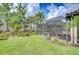 Backyard oasis featuring a screened-in lanai with ample seating, lush lawn, and mature trees at 8433 Alberata Vista Dr, Tampa, FL 33647
