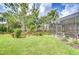 Backyard oasis featuring a screened-in lanai with ample seating, lush lawn, and mature trees at 8433 Alberata Vista Dr, Tampa, FL 33647
