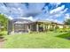 Expansive backyard featuring a screened-in lanai, lush lawn, mature trees, and meticulously maintained landscaping at 8433 Alberata Vista Dr, Tampa, FL 33647
