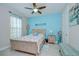 Comfortable bedroom featuring a wooden bed frame, beachy decor, and light blue accent wall at 8433 Alberata Vista Dr, Tampa, FL 33647