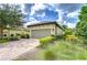 Charming home featuring a tile roof, two-car garage, brick paver driveway, and lush landscaping at 8433 Alberata Vista Dr, Tampa, FL 33647