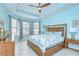 Light filled primary bedroom features a ceiling fan, tray ceiling and large windows at 8433 Alberata Vista Dr, Tampa, FL 33647