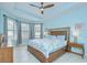 Bright primary bedroom with tray ceiling, ceiling fan, and large windows at 8433 Alberata Vista Dr, Tampa, FL 33647