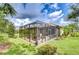 Enclosed screened porch featuring a brick patio under a modern, black metal enclosure in a landscaped backyard at 8433 Alberata Vista Dr, Tampa, FL 33647