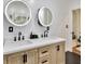 Bright bathroom featuring double sink vanity with wood cabinets and modern, round, lighted mirrors at 9615 Raiden Ln, Riverview, FL 33569