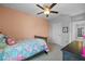bedroom featuring ceiling fan, area rug, salmon accent wall, and view of entry hallway at 16121 Soft Fern Trace, Odessa, FL 33556