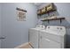 Laundry room featuring a washer, dryer, mounted shelves, and laundry themed decoration at 16121 Soft Fern Trace, Odessa, FL 33556