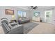 Open-concept living room featuring plush gray sofa, ceiling fan, and tile flooring at 16121 Soft Fern Trace, Odessa, FL 33556