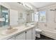 Bathroom with double sinks, white cabinets, large mirror and a shower/tub combo at 10208 Evening Trail Dr, Riverview, FL 33569