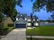 Charming two-story home with a well-manicured lawn and mature trees at dusk at 10208 Evening Trail Dr, Riverview, FL 33569