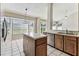 Bright kitchen featuring a central island, tiled flooring, wood cabinets, and a window overlooking the yard at 10208 Evening Trail Dr, Riverview, FL 33569