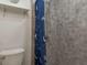 Bathroom with a toilet, gray tiled shower and a shower curtain with nautical anchors at 10623 103Rd St, Largo, FL 33773