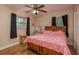 Bedroom showcasing wood floors, a ceiling fan, and a cozy bed with a pink comforter at 10623 103Rd St, Largo, FL 33773