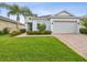 Charming single-Gathering home features lush green lawn, brick driveway, and neutral exterior paint at 10669 Cardera Dr, Riverview, FL 33578