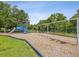 Community playground with a blue slide and swing set surrounded by mature trees and a black fence at 10669 Cardera Dr, Riverview, FL 33578